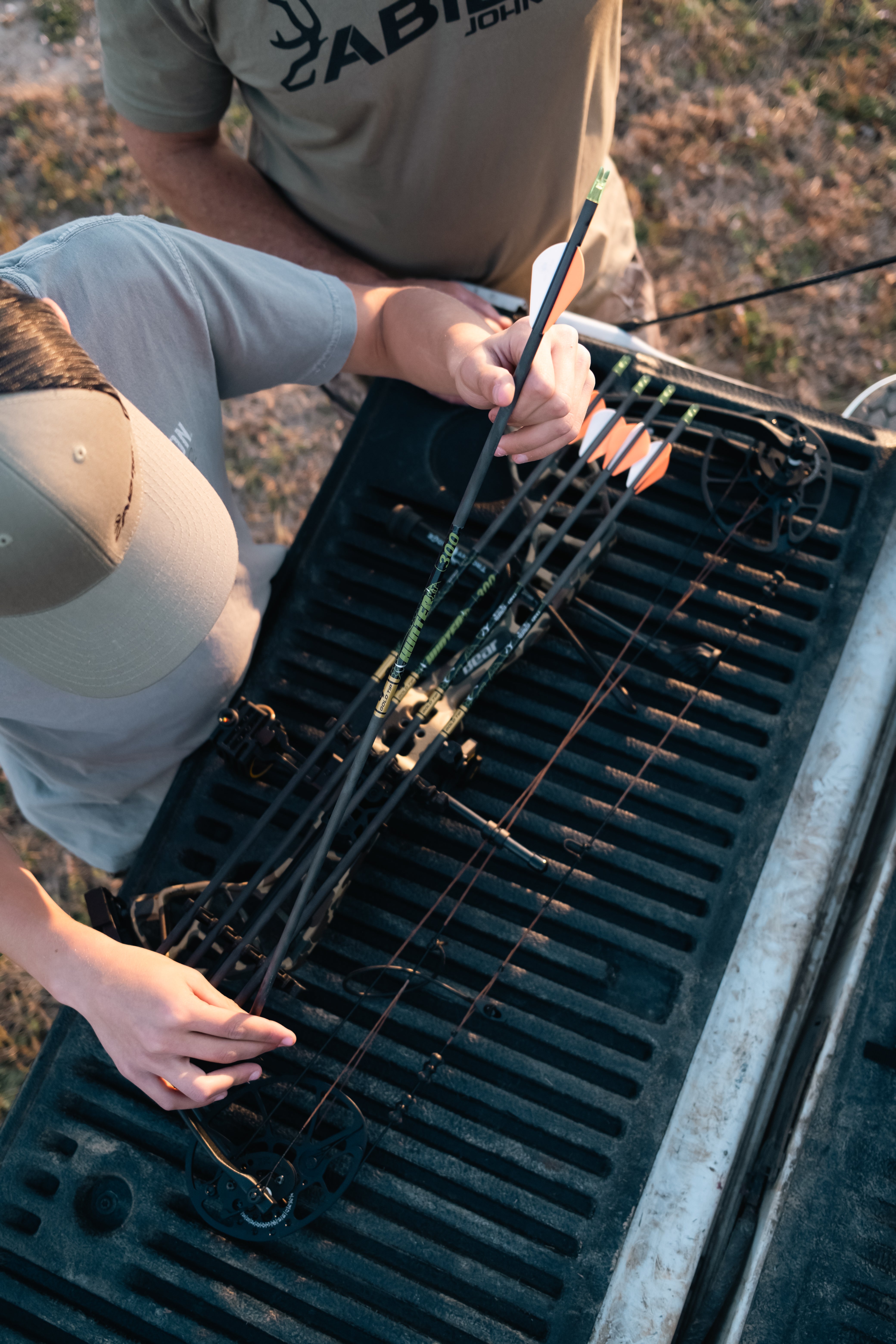 Two people setting up Gold Tip Hunter XT arrows on a vehicle's bed.